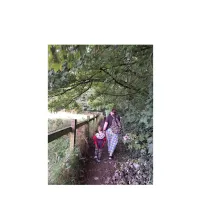 women with a child walking in the path surrounded by trees.