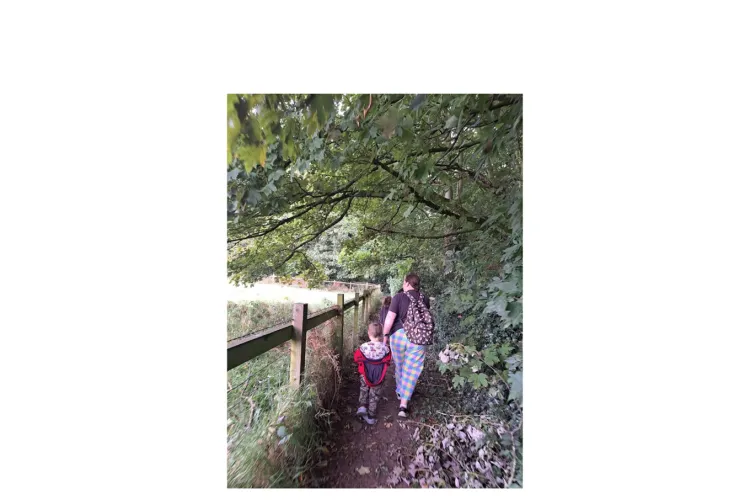 women with a child walking in the path surrounded by trees.